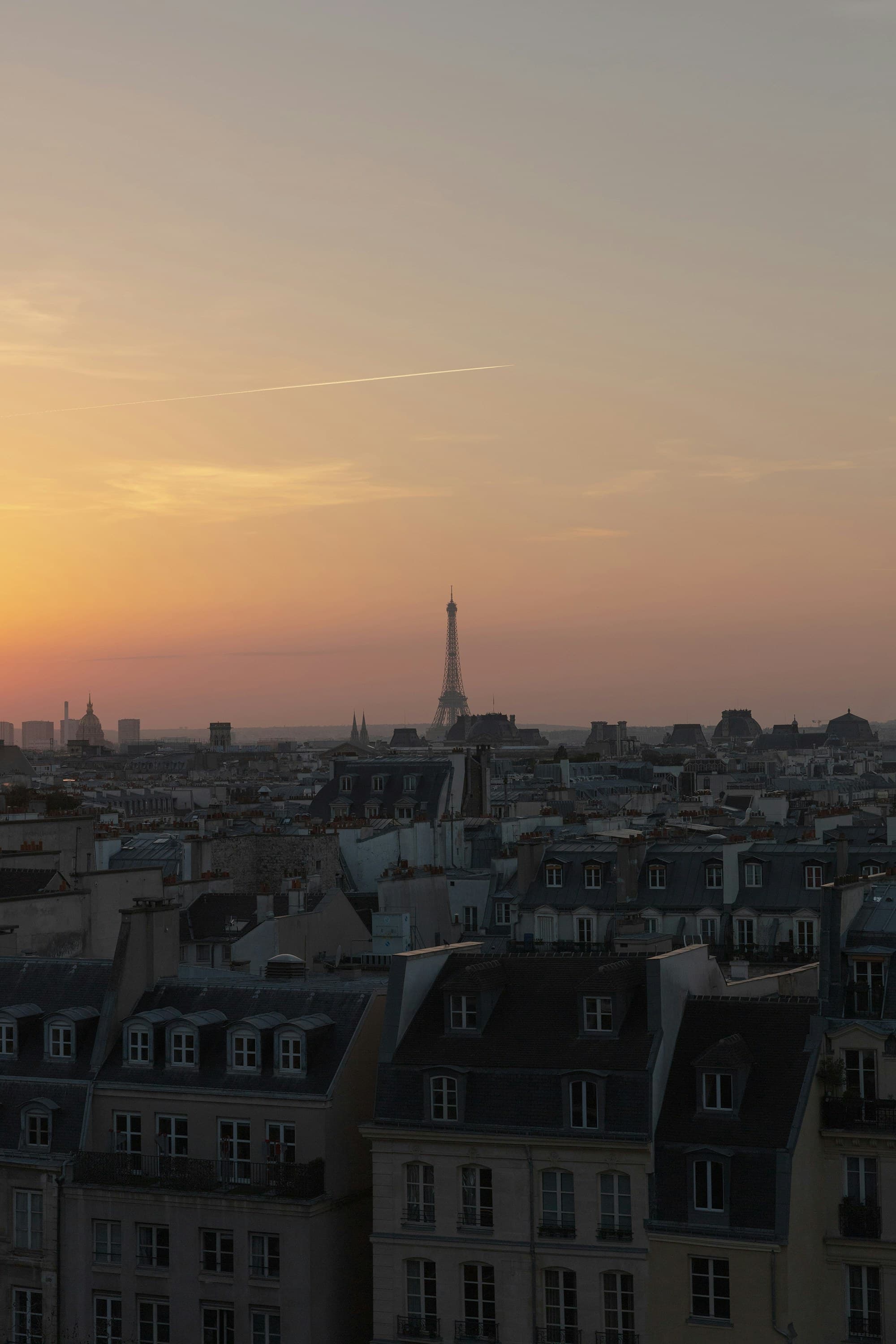 Les toits de Paris au coucher de soleil, la Tour Eiffel dans la brume dorée