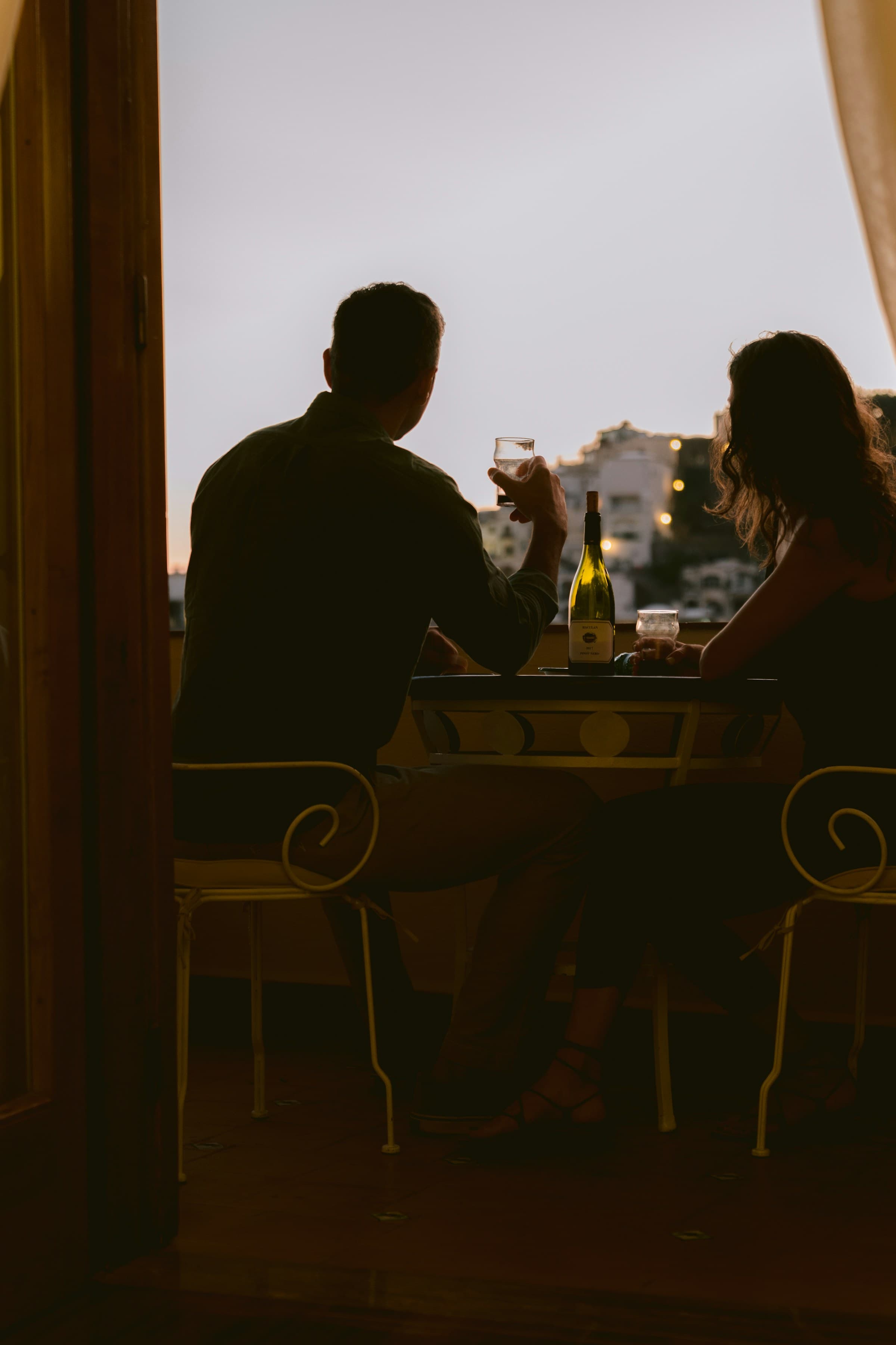 Couple en silhouette face au coucher de soleil, un verre à la main